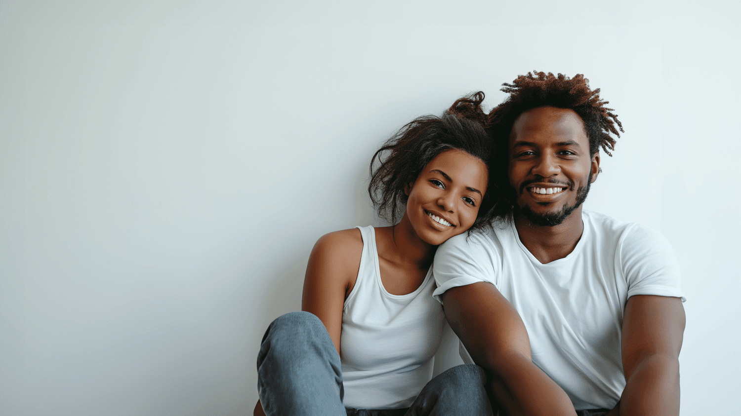 A smiling couple sitting close together, her head resting on his shoulder