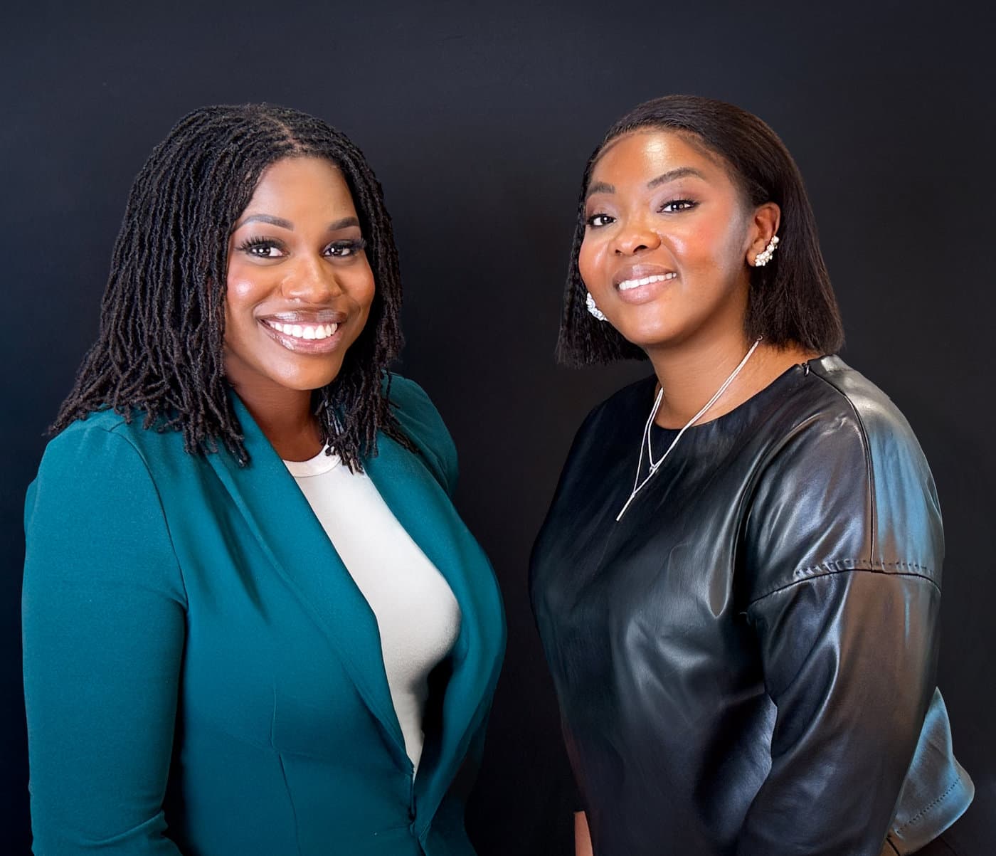 Founding partners Bianca Meant, left, and Reynette Romain, smiling side by side against a dark backdrop